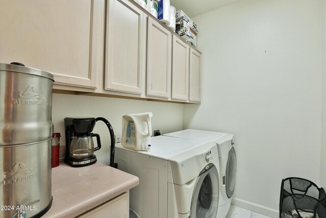 laundry area with light tile patterned floors, washing machine and clothes dryer, and cabinets