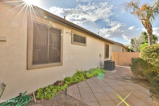 view of side of property with central AC unit and a patio