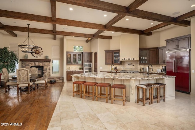 kitchen with built in appliances, custom range hood, a spacious island, and a kitchen bar