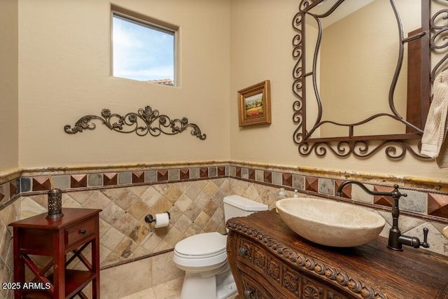 bathroom featuring tile patterned floors, vanity, toilet, and tile walls