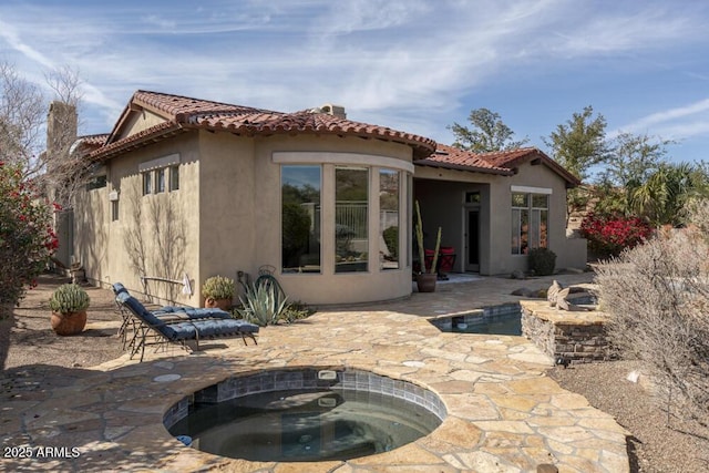 rear view of property with a pool with hot tub and a patio area