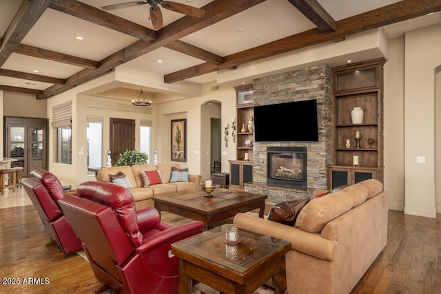 living room featuring coffered ceiling, a stone fireplace, hardwood / wood-style floors, and beam ceiling