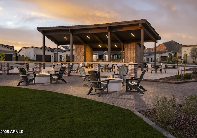 patio terrace at dusk with a fire pit and a yard