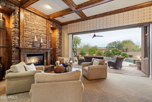 living room featuring coffered ceiling, ceiling fan, a stone fireplace, and beam ceiling