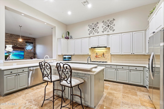 kitchen with appliances with stainless steel finishes, a kitchen breakfast bar, a kitchen island, decorative light fixtures, and kitchen peninsula