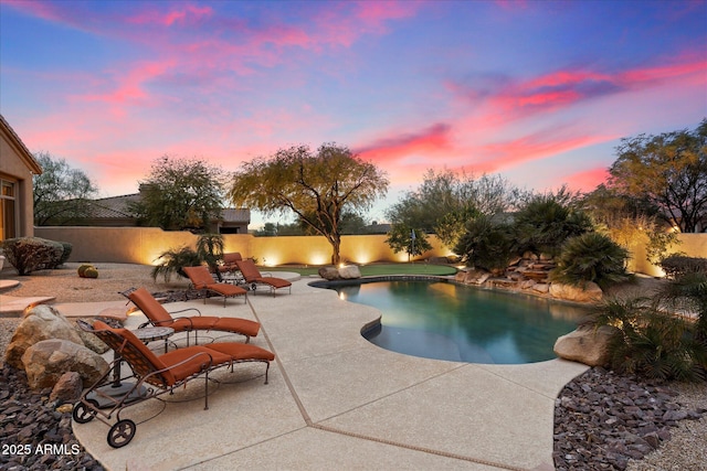 pool at dusk featuring a patio