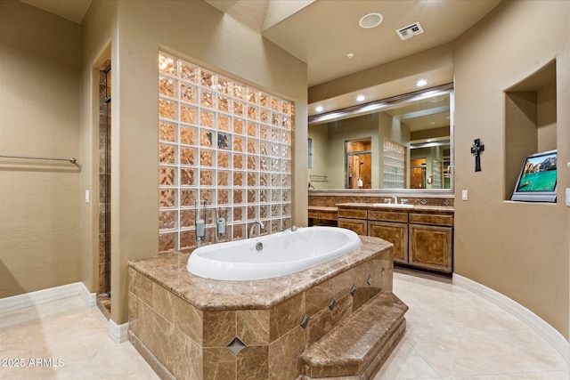 bathroom with tile patterned flooring, vanity, and a relaxing tiled tub