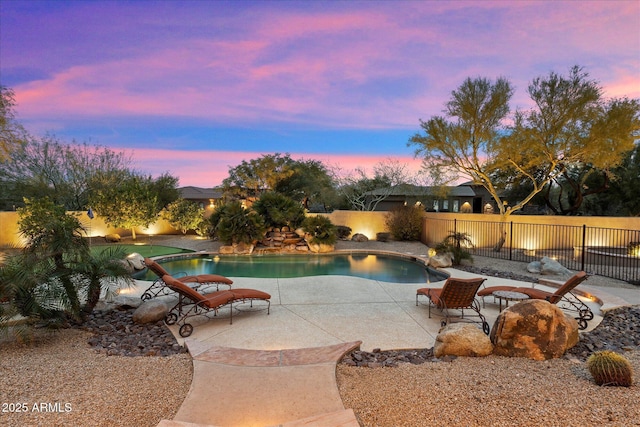 pool at dusk with a patio area