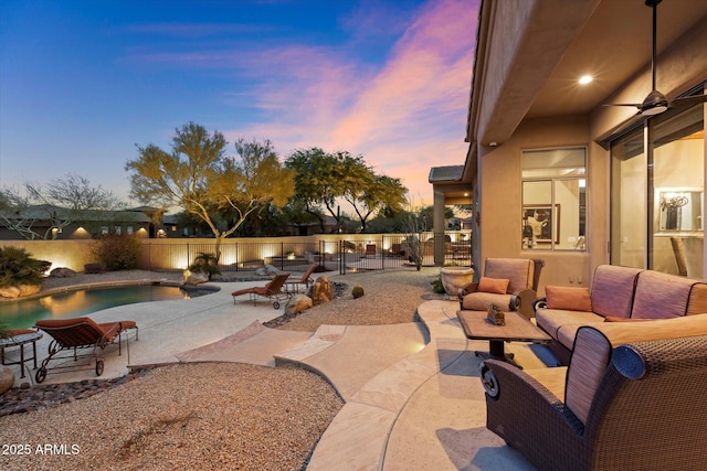 patio terrace at dusk with ceiling fan, outdoor lounge area, and a fenced in pool