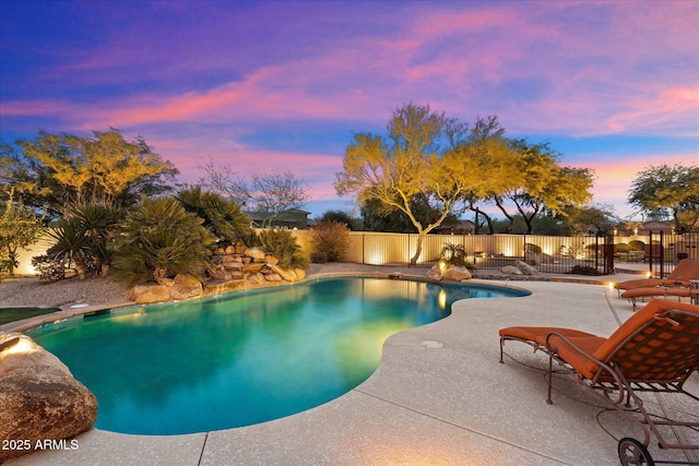 pool at dusk featuring a patio area