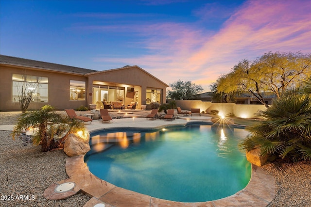 pool at dusk featuring a patio