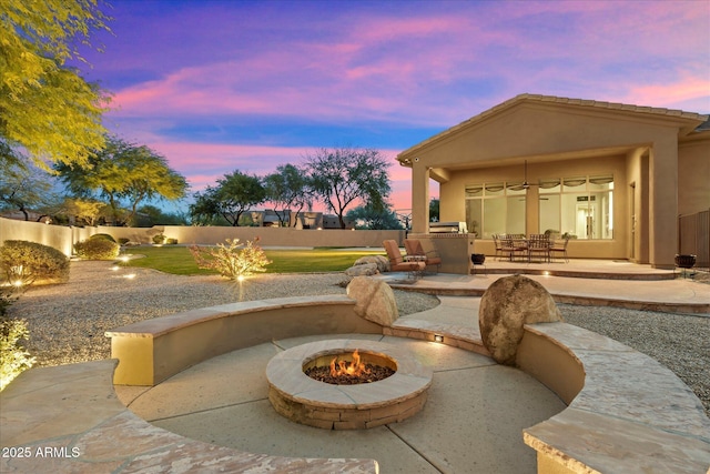 patio terrace at dusk featuring an outdoor kitchen and an outdoor fire pit