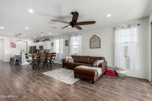 living room with plenty of natural light, ceiling fan, sink, and dark wood-type flooring