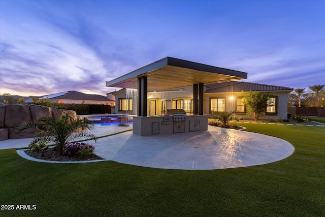 4547 S Banning Dr, Gilbert, AZ 85297 - back of house at dusk featuring exterior kitchen, a fenced in pool, a patio, and a lawn