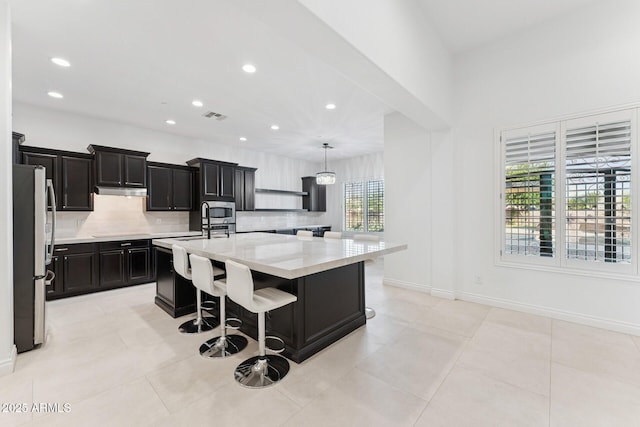4547 S Banning Dr, Gilbert, AZ 85297 - kitchen with freestanding refrigerator, dark cabinets, visible vents, a large island, and backsplash