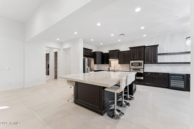 4547 S Banning Dr, Gilbert, AZ 85297 - kitchen with visible vents, appliances with stainless steel finishes, a kitchen bar, wine cooler, and decorative backsplash