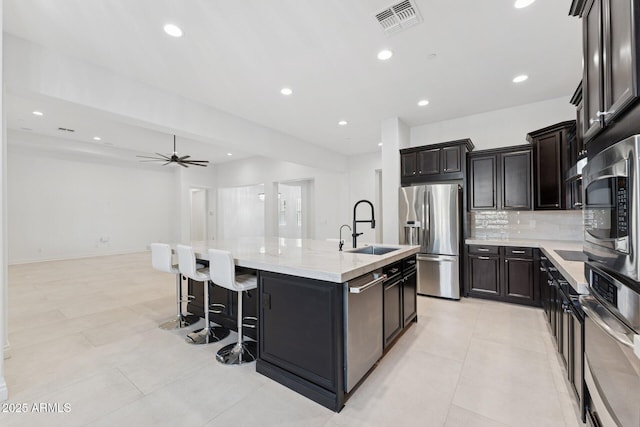 4547 S Banning Dr, Gilbert, AZ 85297 - kitchen with visible vents, appliances with stainless steel finishes, a sink, a center island with sink, and backsplash