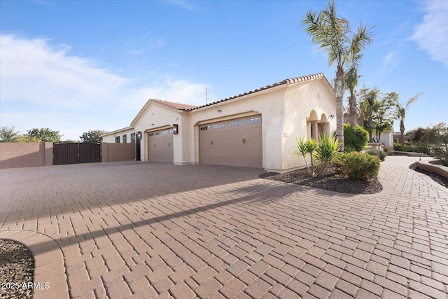 4547 S Banning Dr, Gilbert, AZ 85297 - view of side of home with a tiled roof, an attached garage, stucco siding, a gate, and decorative driveway