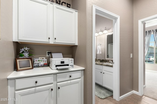 interior space with light tile patterned flooring, sink, and white cabinets