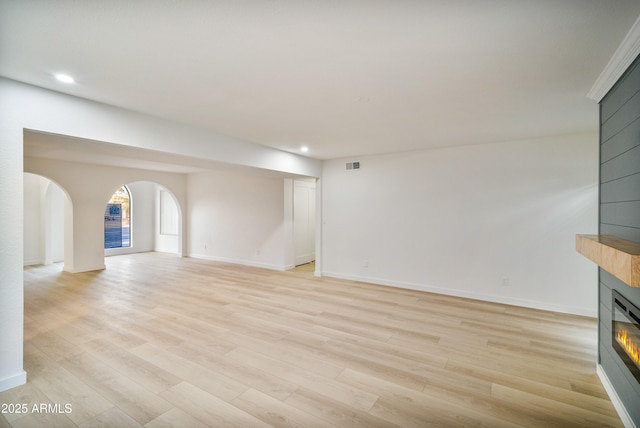 6739 E Thunderbird Rd, Scottsdale, AZ 85254 - unfurnished living room with a fireplace, recessed lighting, light wood-style flooring, and arched walkways