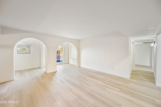6739 E Thunderbird Rd, Scottsdale, AZ 85254 - unfurnished living room featuring baseboards, arched walkways, and light wood-style floors