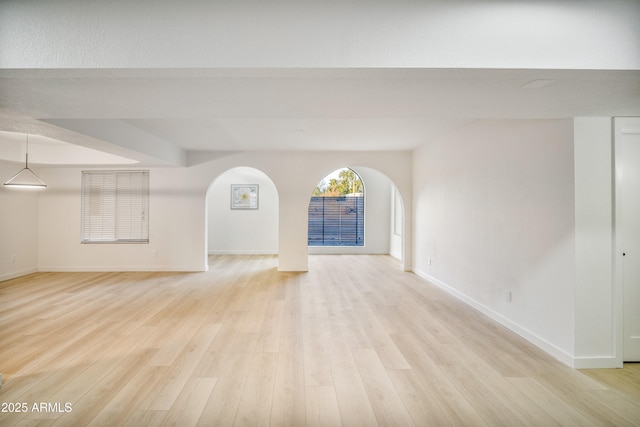 6739 E Thunderbird Rd, Scottsdale, AZ 85254 - unfurnished living room featuring baseboards, light wood finished floors, and arched walkways