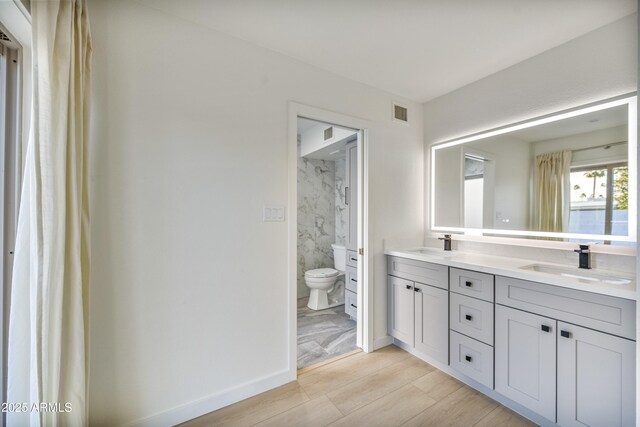 6739 E Thunderbird Rd, Scottsdale, AZ 85254 - bathroom with wood finished floors, toilet, double vanity, and a sink