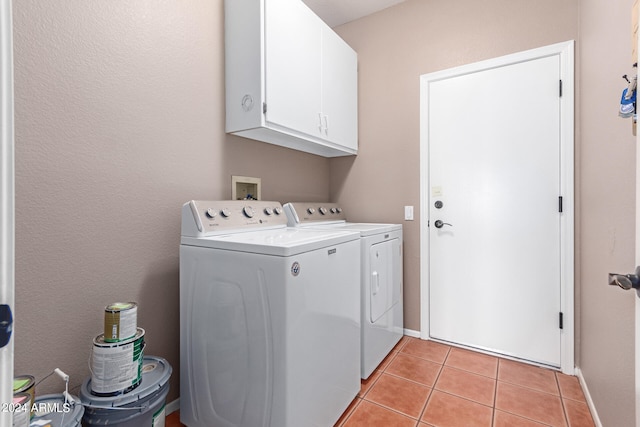 laundry area with washing machine and clothes dryer, light tile patterned flooring, and cabinets