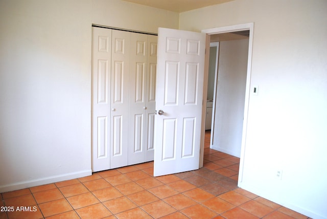 unfurnished bedroom with light tile patterned floors, a closet, and baseboards