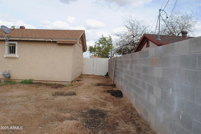 view of property exterior with stucco siding, roof with shingles, and fence