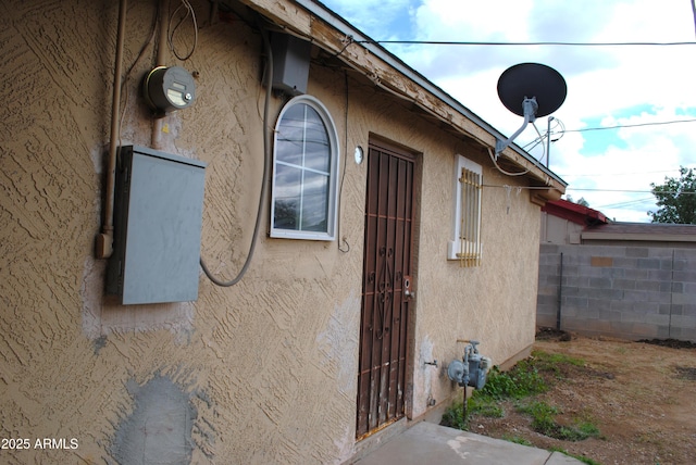 view of property exterior with stucco siding and fence