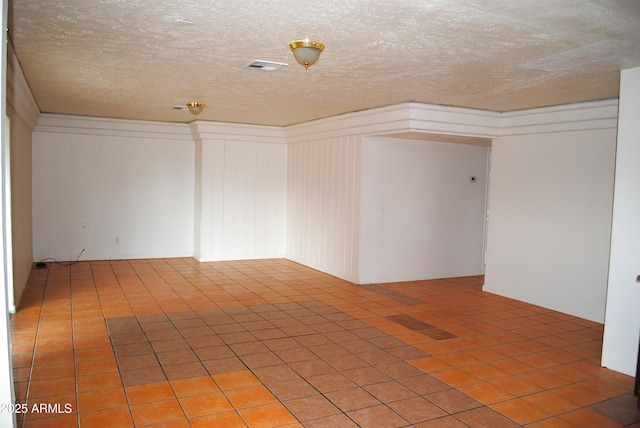 unfurnished room featuring light tile patterned floors, visible vents, and a textured ceiling