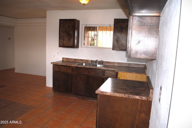 kitchen featuring a sink, dark countertops, dark brown cabinetry, and tile patterned floors