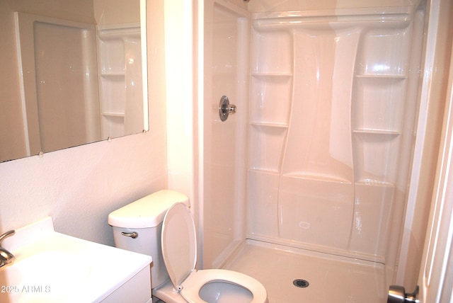 bathroom featuring a stall shower, toilet, and vanity