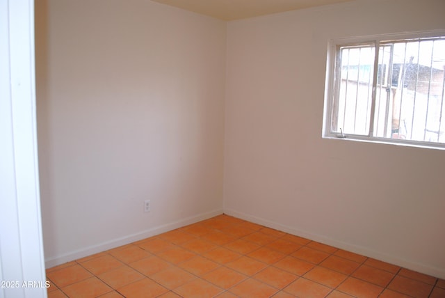 empty room featuring light tile patterned floors and baseboards