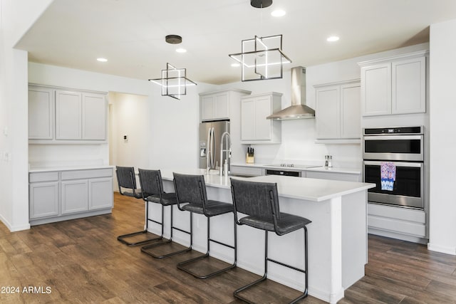 7180 W Tombstone Trl, Peoria, AZ 85383 - kitchen with wall chimney exhaust hood, stainless steel appliances, a sink, a kitchen breakfast bar, and dark wood finished floors