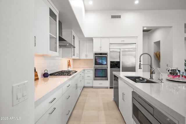 7775 E Fledgling Dr, Scottsdale, AZ 85255 - kitchen with wall chimney exhaust hood, stainless steel appliances, tasteful backsplash, recessed lighting, and white cabinetry