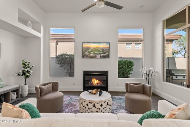 7775 E Fledgling Dr, Scottsdale, AZ 85255 - living room with wood finished floors, healthy amount of natural light, a glass covered fireplace, and a ceiling fan