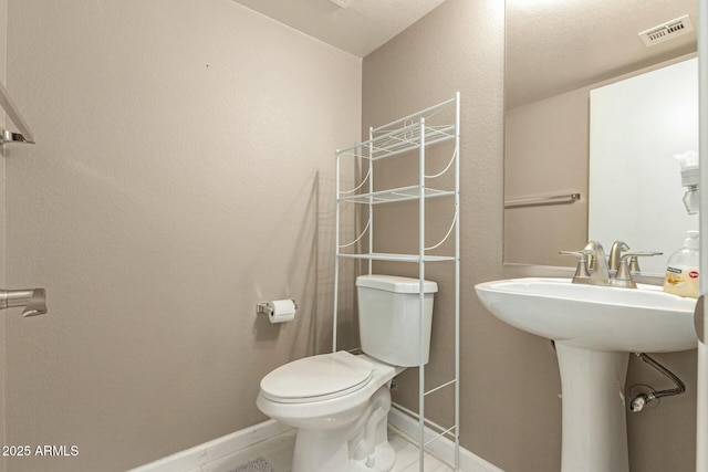 bathroom featuring toilet, baseboards, visible vents, and a sink