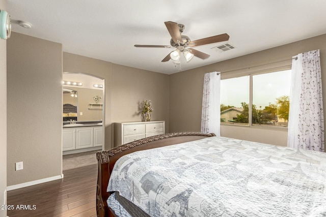 bedroom featuring arched walkways, visible vents, dark wood-type flooring, a sink, and baseboards