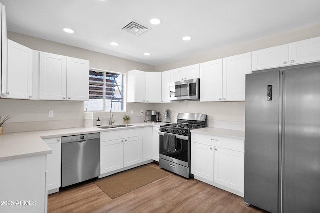 4137 E Sells Dr, Phoenix, AZ 85018 - kitchen featuring appliances with stainless steel finishes, a sink, wood finished floors, white cabinets, and recessed lighting