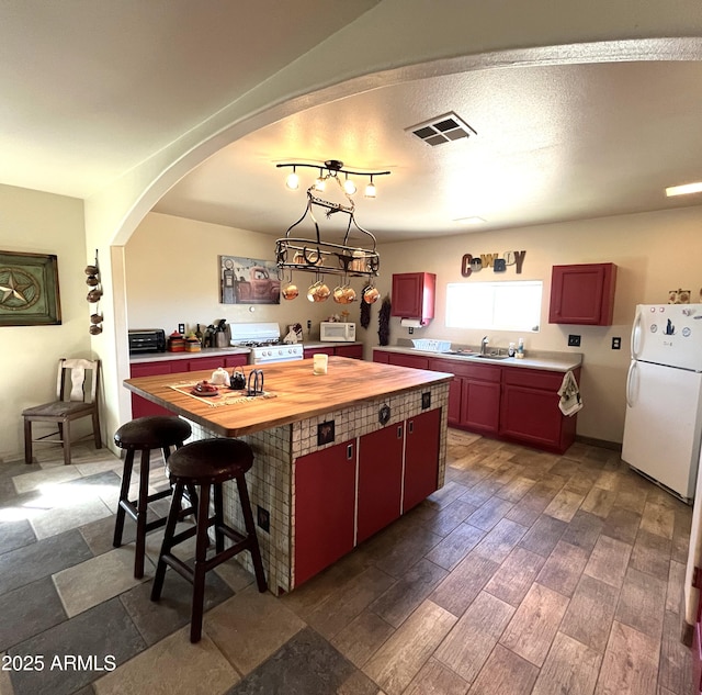 kitchen featuring a kitchen island, butcher block counters, dark wood-type flooring, and white appliances