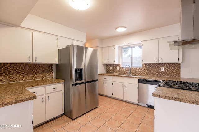 kitchen featuring appliances with stainless steel finishes, range hood, sink, white cabinets, and decorative backsplash