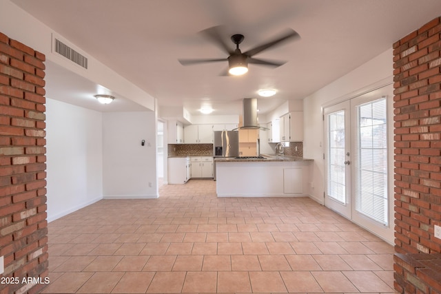 kitchen with french doors, white cabinetry, appliances with stainless steel finishes, kitchen peninsula, and island exhaust hood