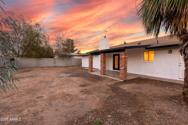 back house at dusk with a patio