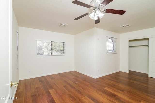 unfurnished bedroom with a closet, dark hardwood / wood-style floors, and ceiling fan