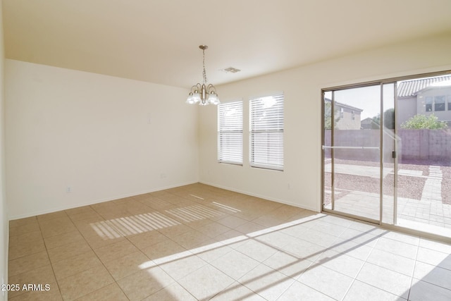 tiled spare room with a notable chandelier