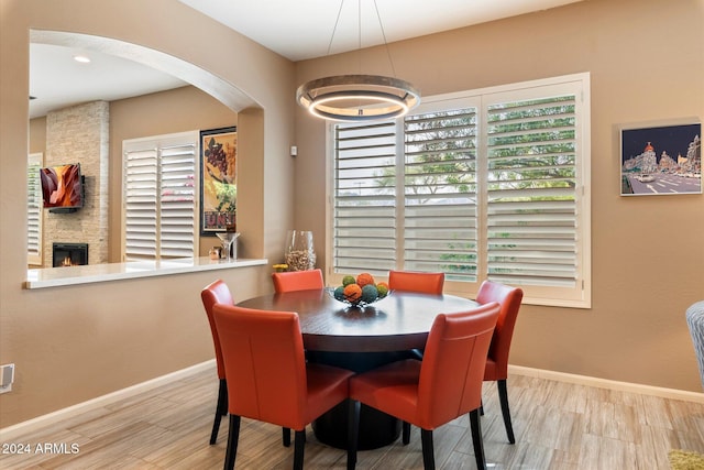 dining space featuring light hardwood / wood-style flooring and a stone fireplace