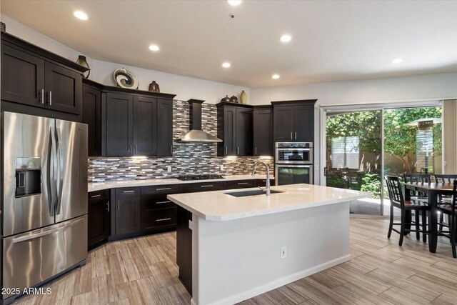 7979 E Princess Dr Unit 13, Scottsdale, AZ 85255 - kitchen featuring wall chimney exhaust hood, appliances with stainless steel finishes, a breakfast bar, decorative backsplash, and recessed lighting