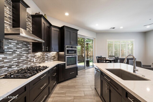 7979 E Princess Dr Unit 13, Scottsdale, AZ 85255 - kitchen with wall chimney range hood, appliances with stainless steel finishes, arched walkways, backsplash, and recessed lighting